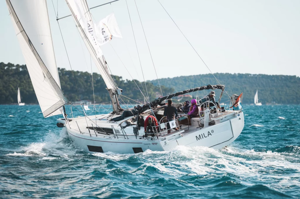 Segelboot „MILA 8“ mit Crew bei starkem Wind auf bewegter See während einer Regatta.