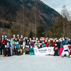 Gruppenfoto der Teilnehmer in Ski-Kluft im Schnee, im Hintergrund Berge und Tannebäume